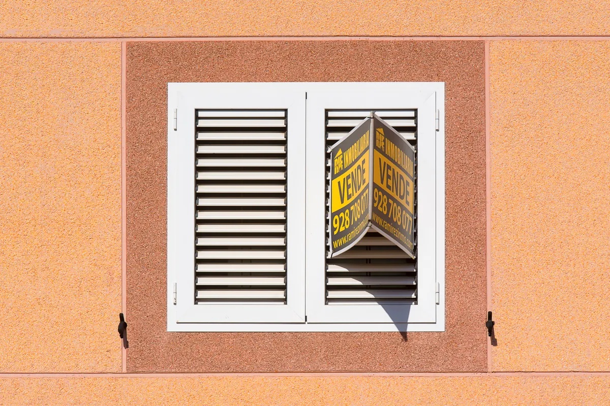 Fachada de edificio de viviendas con cartel de se vende, ilustrando la venta de casas embargadas de bancos en España