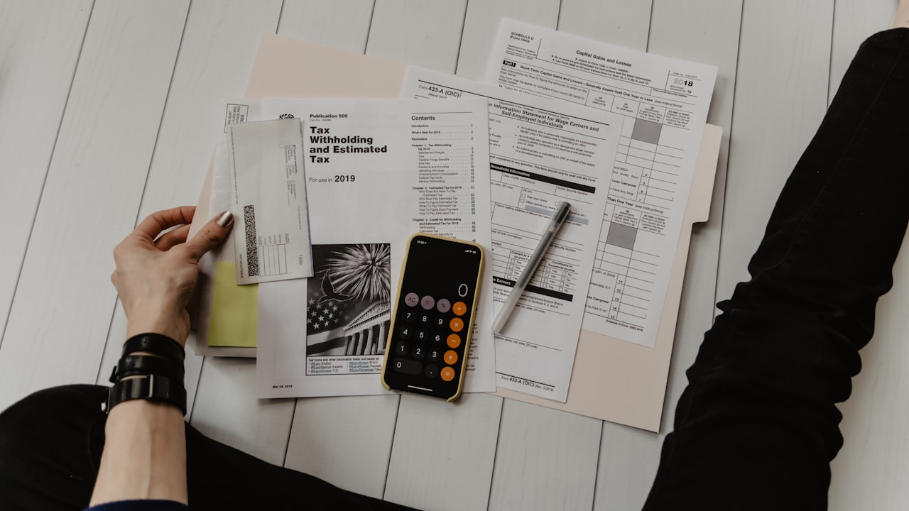 Persona revisando documentación registral y notas legales sobre una mesa antes de pujar en una subasta inmobiliaria